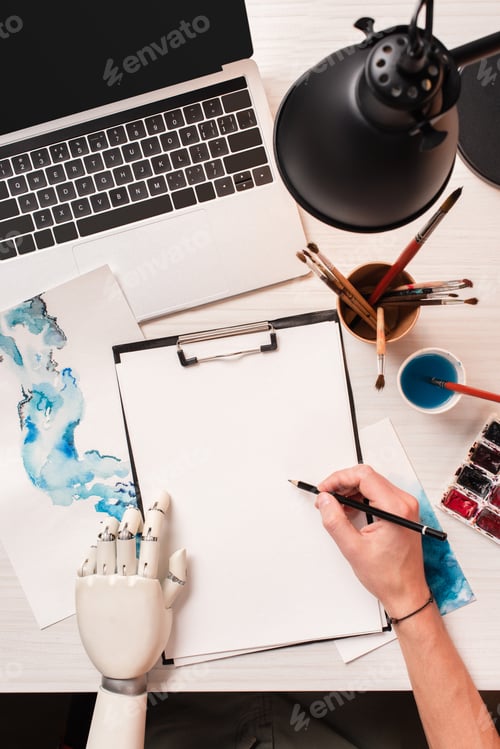 Preview: office desk with laptop, blank sheet and cropped female hand with robot hand, flat lay
