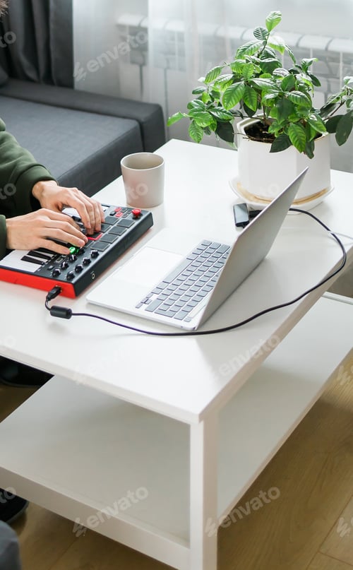 Preview: Man recording electronic music track with portable midi keyboard on laptop computer in home studio