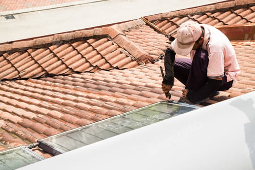 Preview: Worker fixing solar water heater on roof during maintenance