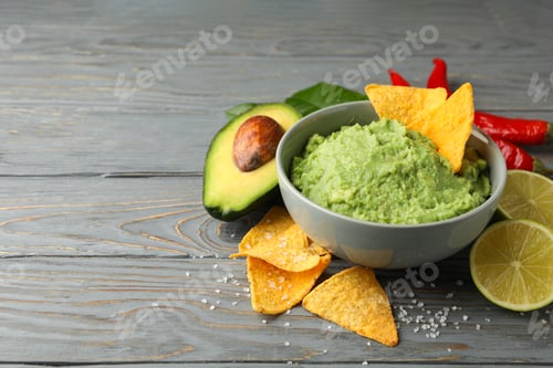 Preview: Concept of tasty eating with bowl of guacamole on wooden background, space for text