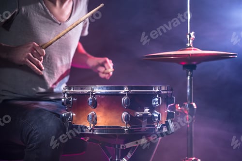 Preview: The drummer plays the drums. Beautiful blue and red background, with rays of light.