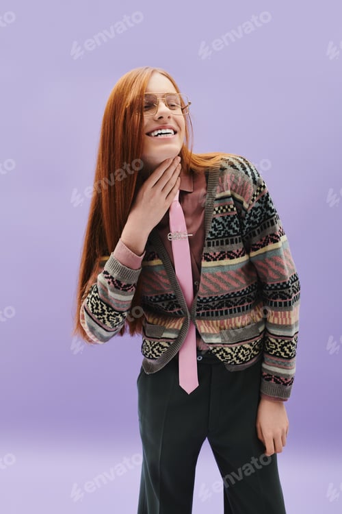 Preview: Fashionable young queer man with long red hair poses stylishly against a soft purple backdrop