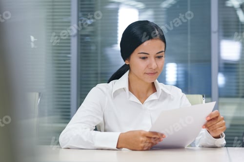 Preview: Pretty young businesswoman reading financial document