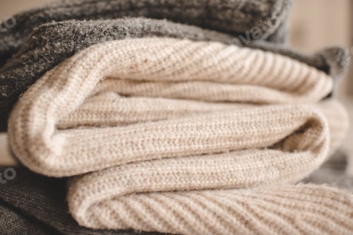 Preview: Folded knit sweaters in bed close up