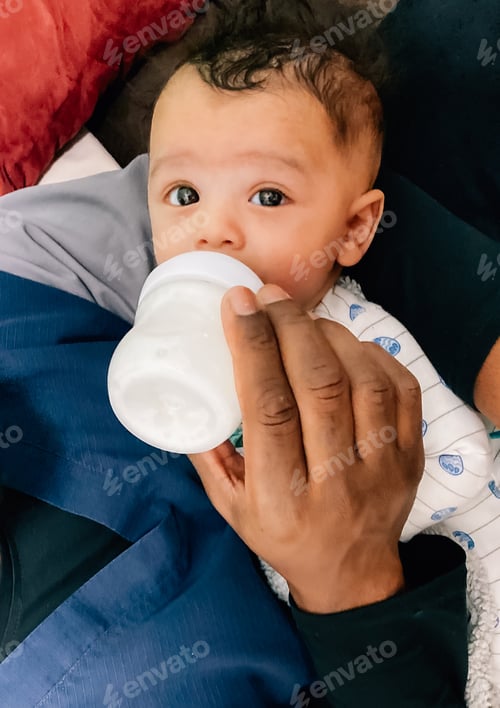 Preview: African American father feeding baby boy from bottle