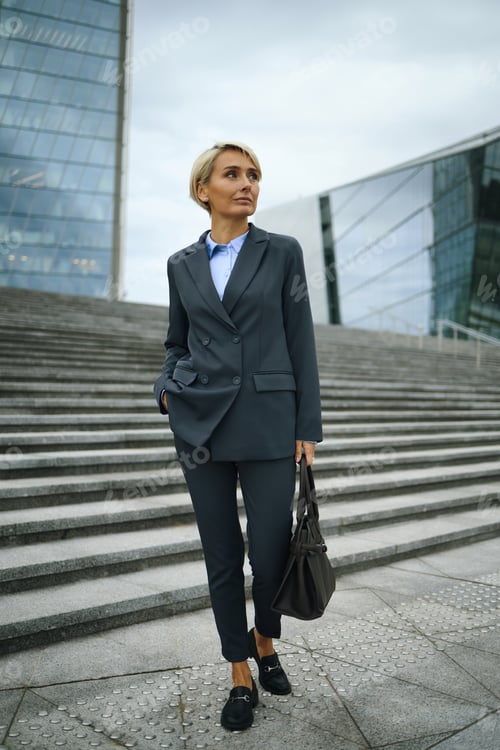 Preview: Caucasian Woman in Suit Walking Outdoors near Modern Office Buildings