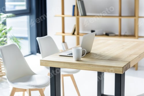 Preview: Laptop and coffe cup on table in modern office