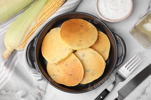 Preview: Tasty corn pancakes and sauce served on white marble table, flat lay