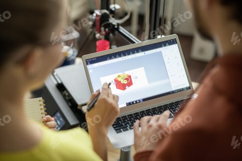 Preview: One of two architects or designers pointing at cube sketch on laptop display