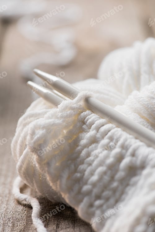 Preview: selective focus of knitted needles and white woolen knitted yarn