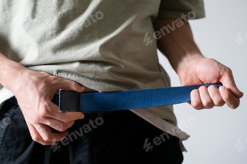 Preview: a young fit man tight the pants belt