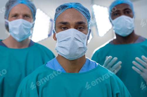 Preview: Portrait of diverse male surgeons wearing surgical gowns in operating theatre at hospital