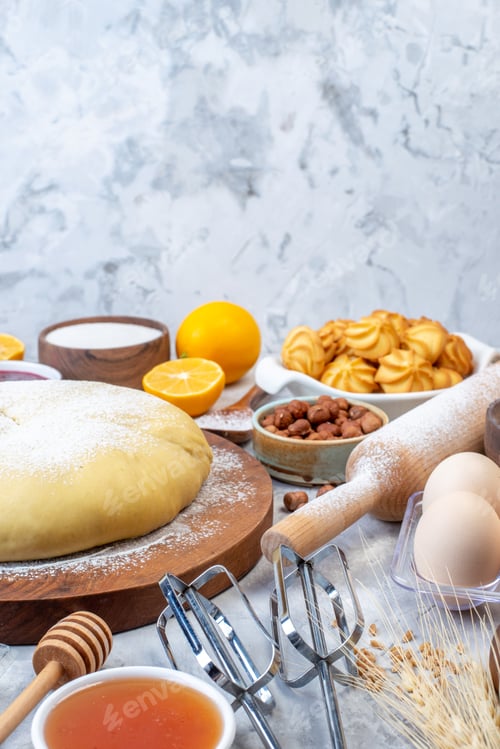 Preview: Vertical view of raw pastry on wooden round board and set of various foods grater on ice background