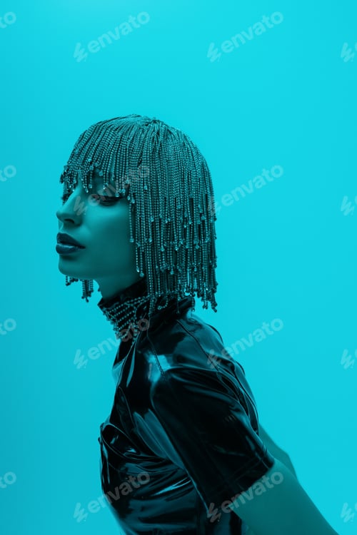 Preview: Pretty woman in luxury headwear and latex top standing isolated on blue with lighting