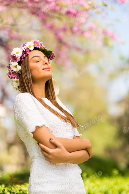 Preview: Young woman with flowers in her hair on sunny spring day