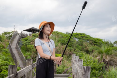 Preview: Woman go hiking and use of 360 camera to take photo and video in countryside