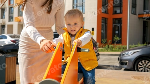 Preview: Cute baby boy riding on the bouncy spring rider on the the playground at amusement park