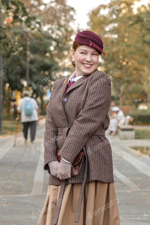 Preview: A brunette in vintage clothes and a hat stands on a path in an autumn park. Retro style