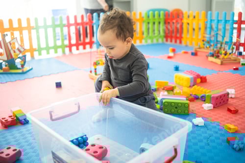 Preview: Toddler boy plays with colorful plastik bricks at children playroom