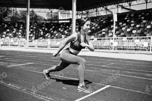 Preview: Portrait of a strong fit girl in sportswear running in the stadium. Black and white photo.
