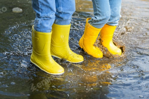 Preview: two children on an active and fun walk through the puddles in the warm season
