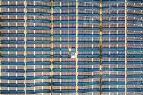 Preview: Aerial view of many photo voltaic solar panels mounted of industrial building roof.
