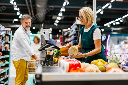 Preview: Cashier scanning groceries at checkout counter in supermarket