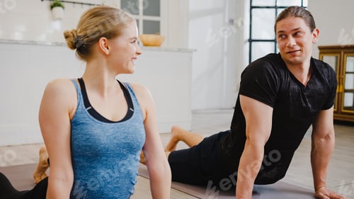 Preview: American couple in sportswear doing yoga exercise working out in kitchen at home.