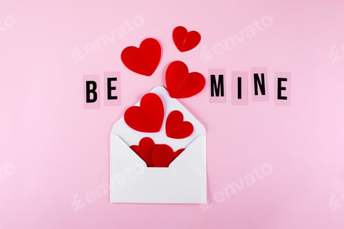 Preview: White envelope, red paper hearts and text Be Mine on pink background. Valentine's day, love concept