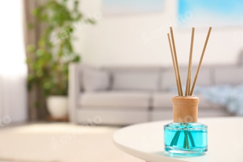 Preview: Reed air freshener with essential oil on table in room. Space for text