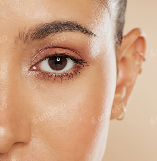 Preview: Eye, vision and beauty with a model woman closeup in studio on a beige background for eyecare or sk