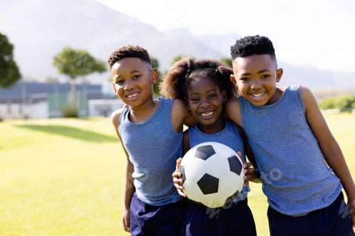Preview: Portrait of happy african american schoolchildren playing football on field at school