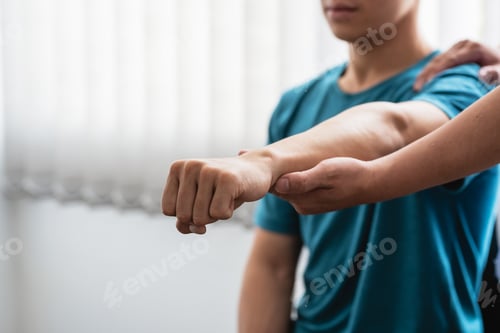 Preview: Physiotherapist treating a man with elbow pain at a clinic.