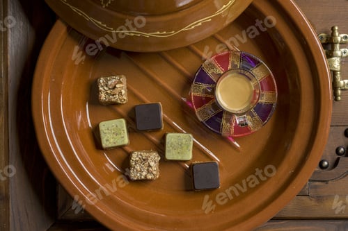 Vorschau: Luftaufnahme verschiedener Arten von quadratischen Süßigkeiten mit Tee auf einem Holztablett