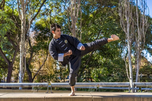 Preview: Martial arts fighter practicing kicks in a public park.