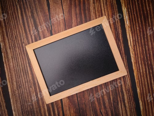 Preview: Top view a plain black chalkboard on a wooden background.