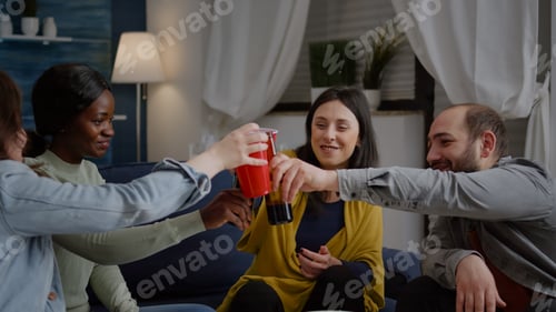 Preview: Mixed race friends chatting during night party while sitting on sofa