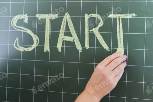 Preview: Start concept, woman's hand with chalk writing the word start on a blackboard