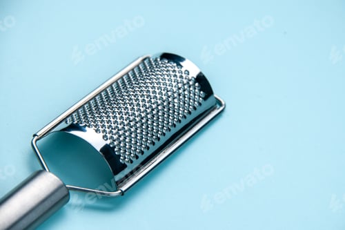 Preview: Front close view of stainless kitchen tool lying on the right side on pastel blue background with