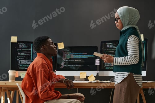 Preview: Two young confident multicultural interns in casualwear looking at each other