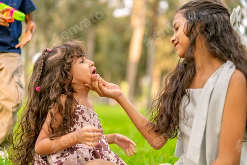 Preview: Older sister showing love to younger sibling outdoors
