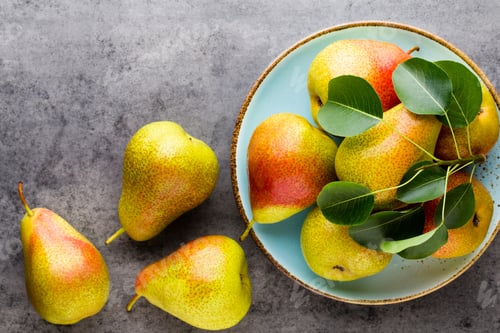 Preview: Fresh bio pear with leaves on the plate. Gray stone table.