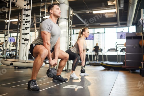 Preview: Couple Doing Squats with Weights in Gym
