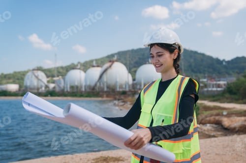 Preview: Assured engineer wearing a safety helmet and high-visibility vest holds blueprints