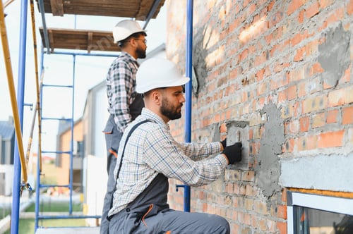 Preview: Construction workers plastering brick wall on building site