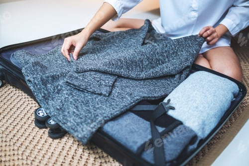 Preview: Closeup image of a woman folding clothes and packing luggage for a trip