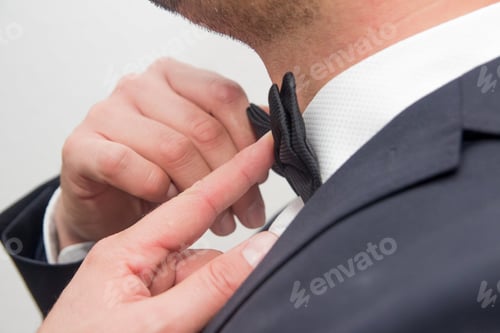 Preview: Closeup shot of a male in a suit fixing his bow