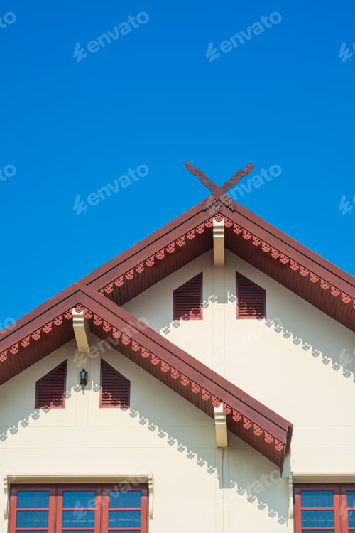 Preview: Vintage house with Kalae carved wood decoration on the upper part of gable roof against blue sky