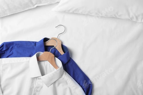 Preview: Stylish shirts on bed, top view. Dry-cleaning service