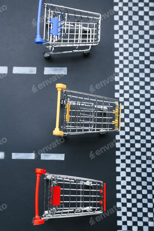 Preview: Competition concept. Shopping carts racing towards finish line, flat lay